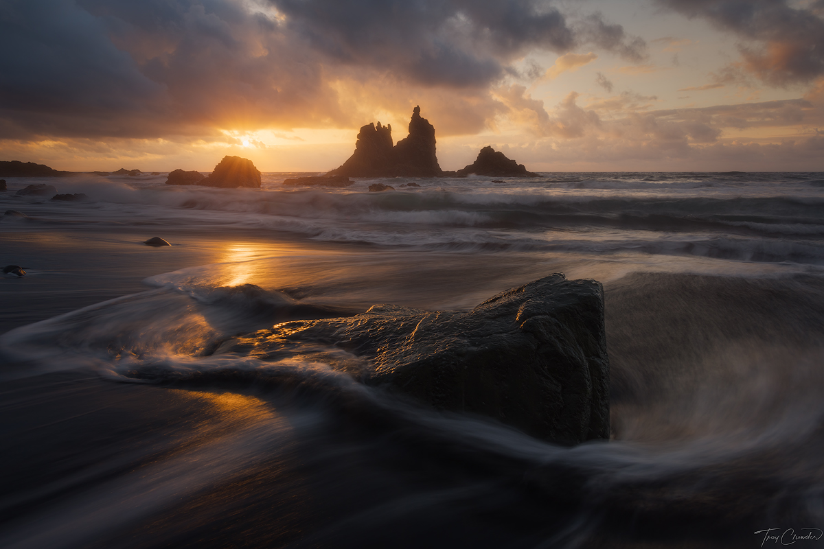 Towering lava rock seastacks at Playa de Benijo. A small gap in the clouds gives way to a radiant sunset.